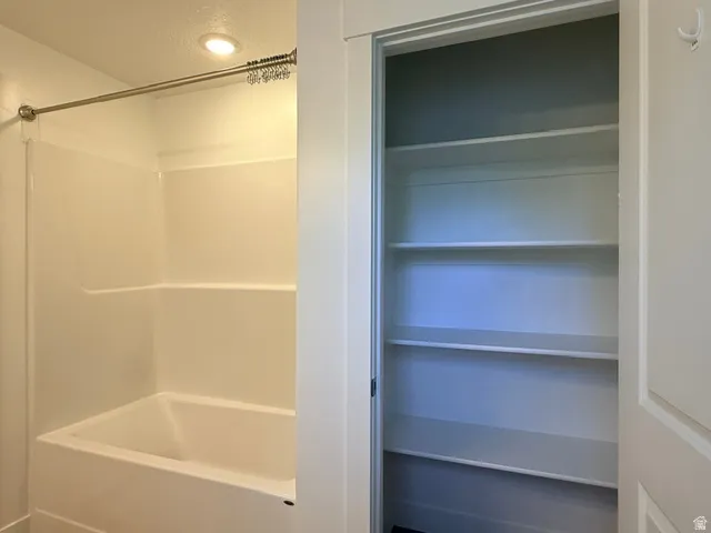 Tub/shower combination with a stainless steel shower rod and adjacent built-in shelving