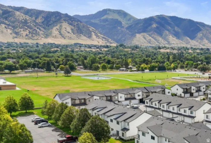 Mountainous terrain backdrop with extensive green spaces and established trees