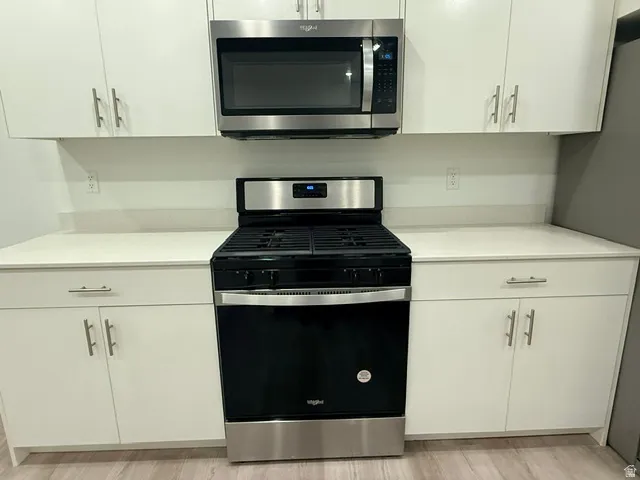 White cabinetry with brushed nickel hardware, stainless steel appliances, and light-toned countertops