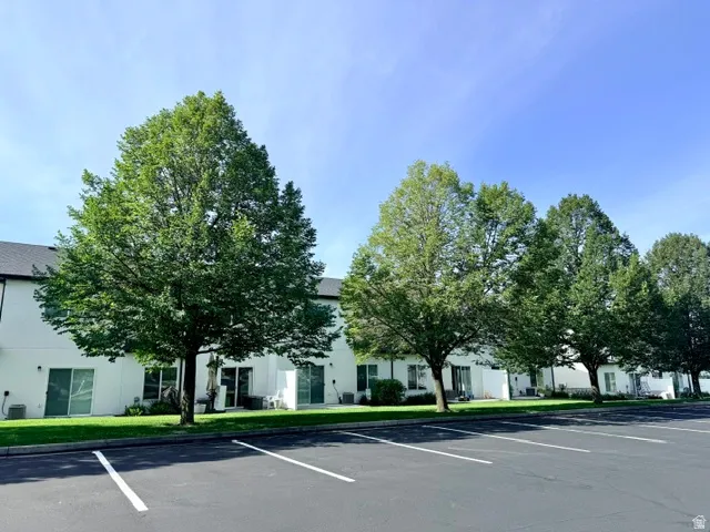 Rear exterior featuring white siding, multiple sliding glass doors, a grass lawn, and mature trees