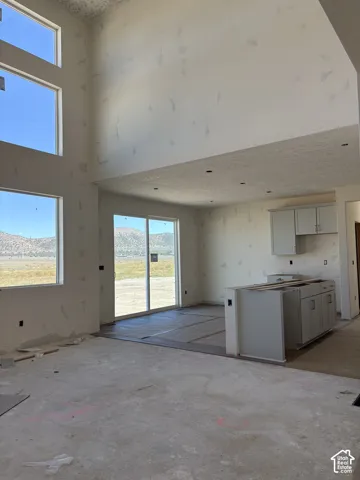 Soaring ceilings with recessed lighting, multiple large windows, sliding glass door access, and kitchen cabinetry with a central island