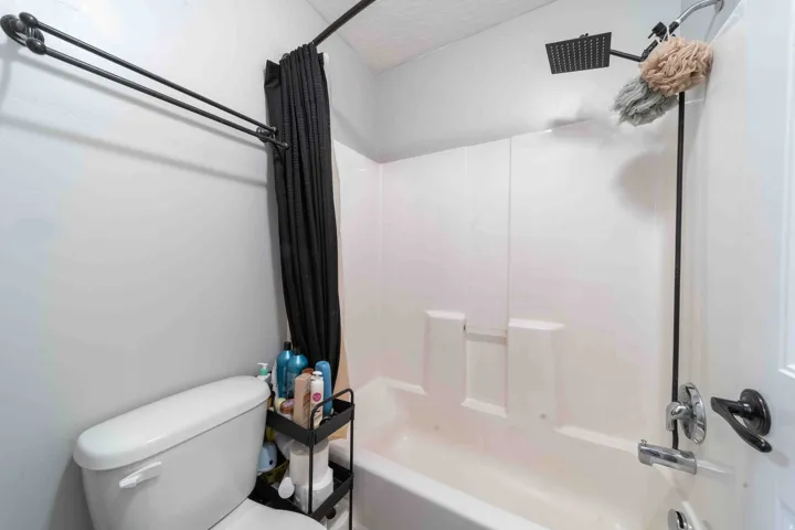 White bathtub with shower, square rain showerhead, and black shower curtain rod