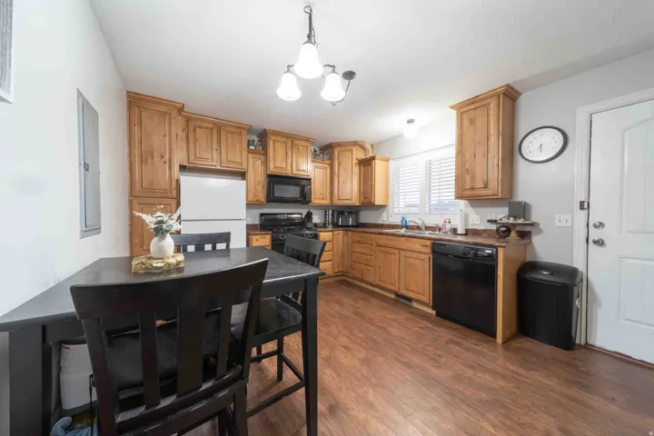 Spacious kitchen featuring warm wood cabinetry, black stainless steel appliances, and dark wood-finish flooring throughout