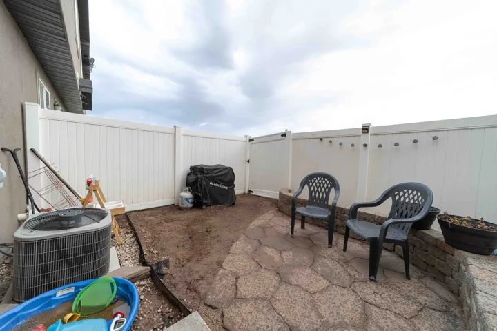 Paved patio area featuring flagstone-style pavers and a white privacy fence
