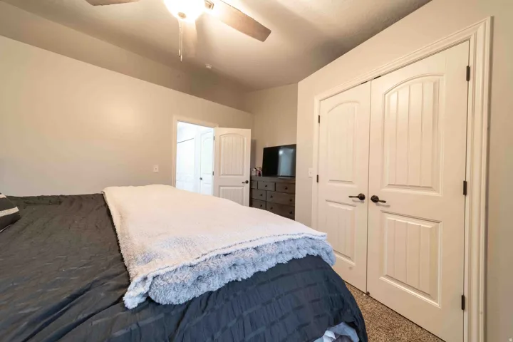 Double white paneled doors with black hardware, ceiling fan with integrated lighting, and neutral wall tones