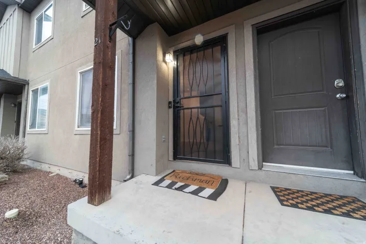 Stucco exterior with multiple windows, a security screen door, and a solid entry door