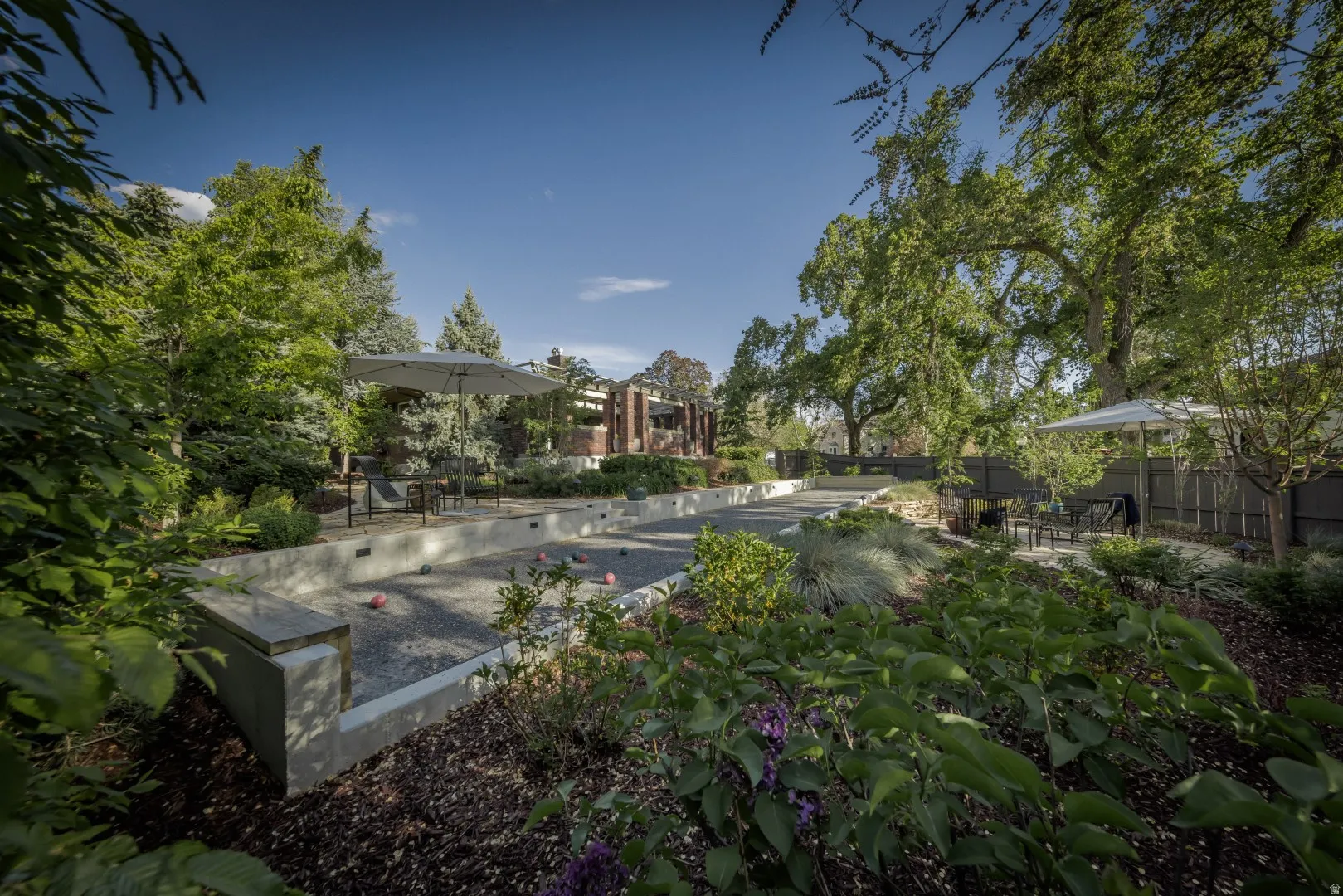 Serene backyard oasis featuring mature landscaping, lush perimeter plantings, and a central water feature with stone edging