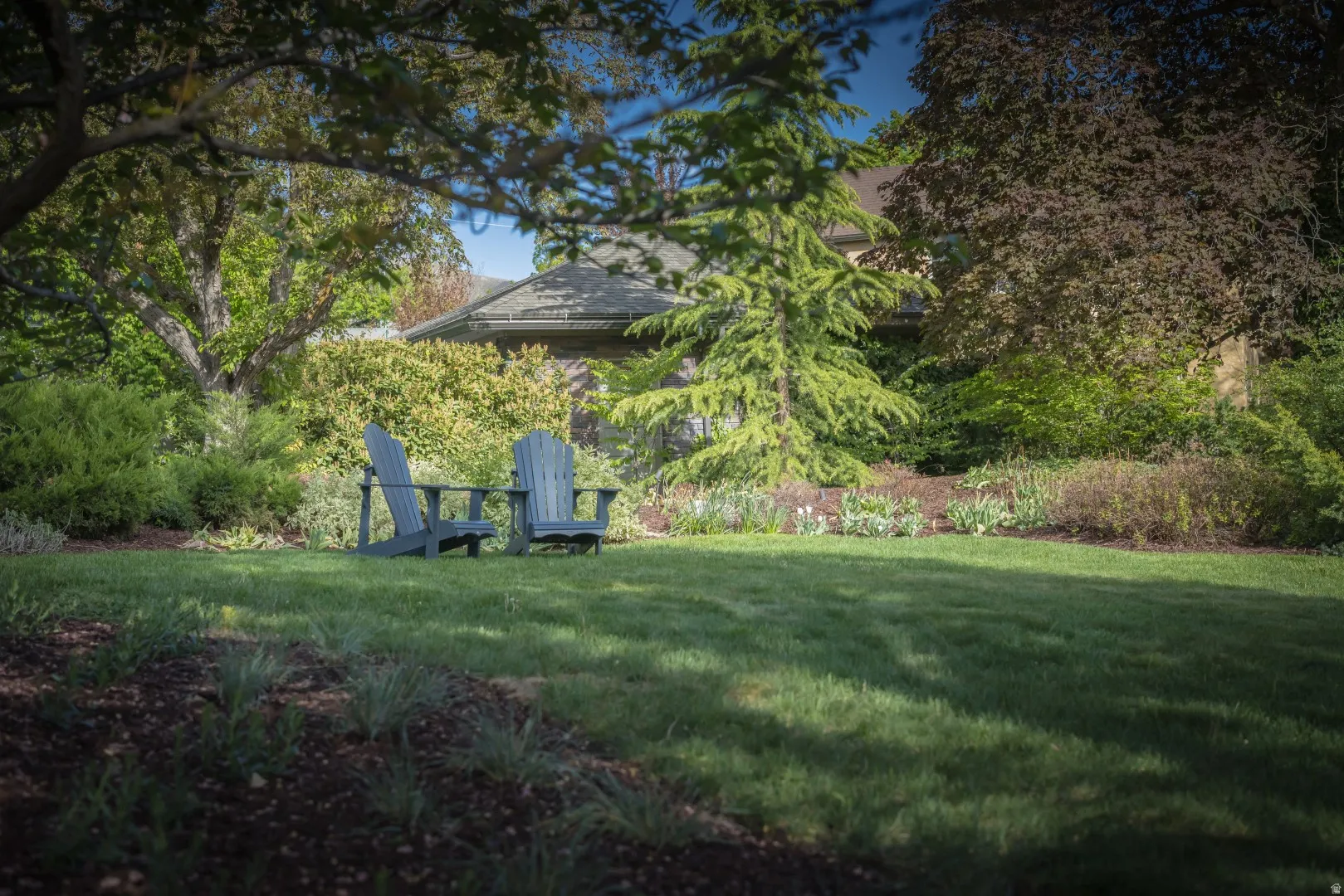 Expansive lawn with mature landscaping and established garden beds
