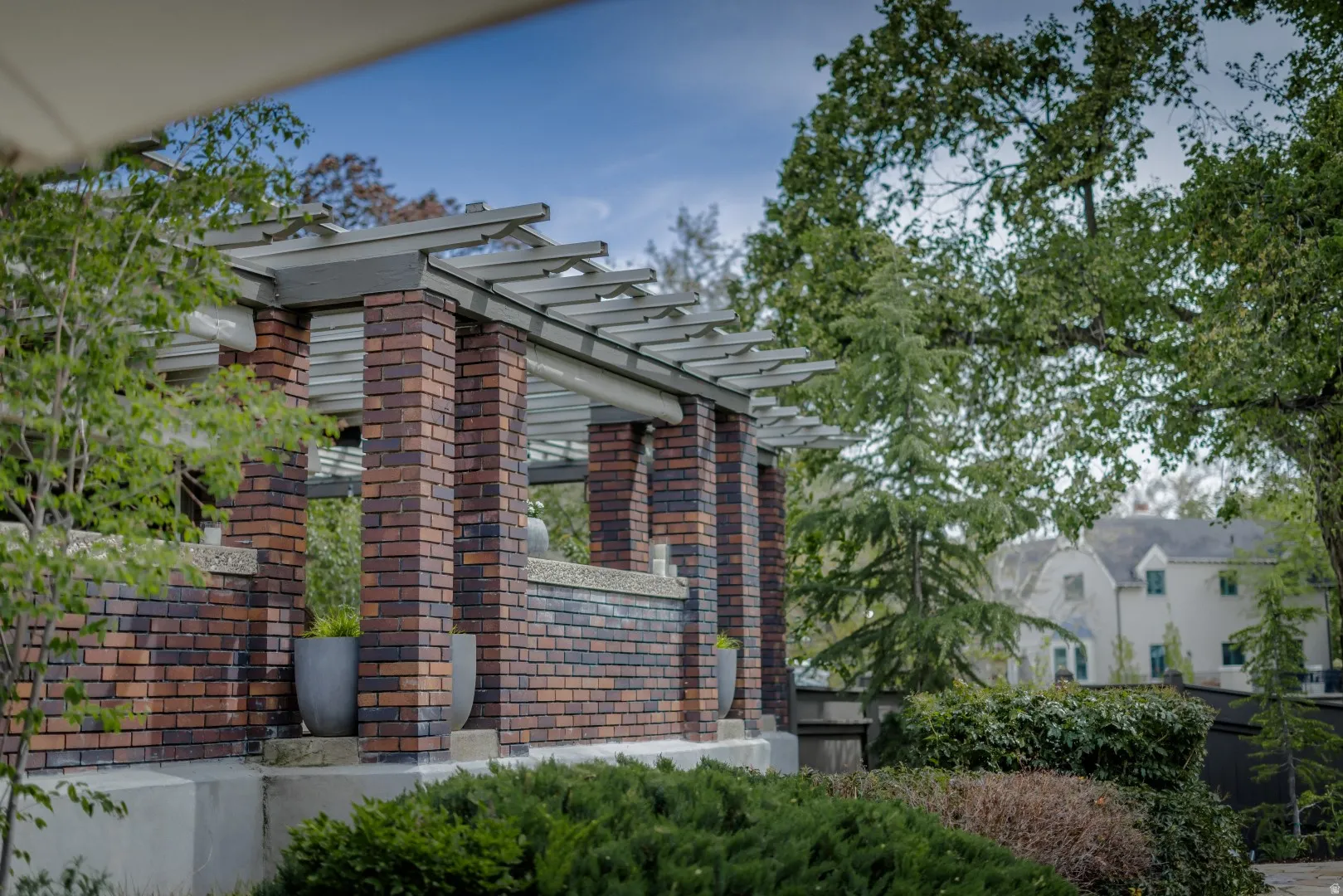 Brick-clad columns supporting a slatted pergola structure