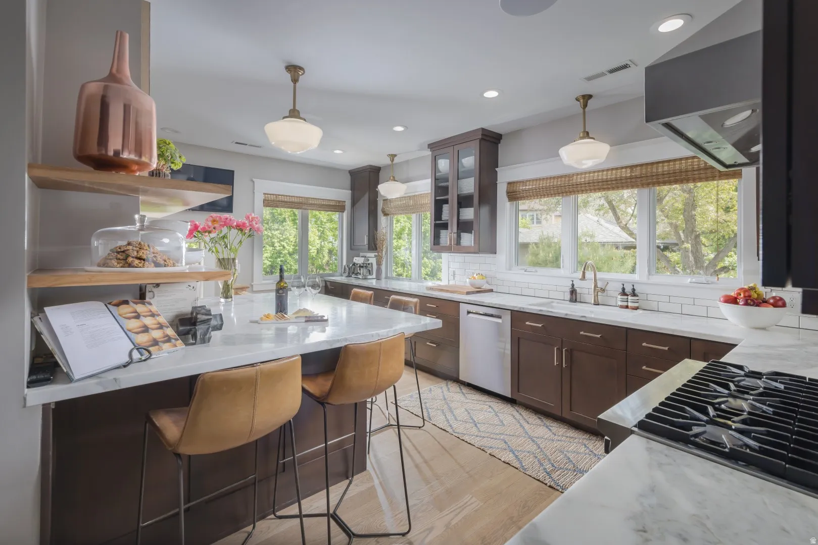 Island with stone countertop, dark wood-finish cabinetry, subway tile backsplash, stainless steel appliances, and wood-finish flooring