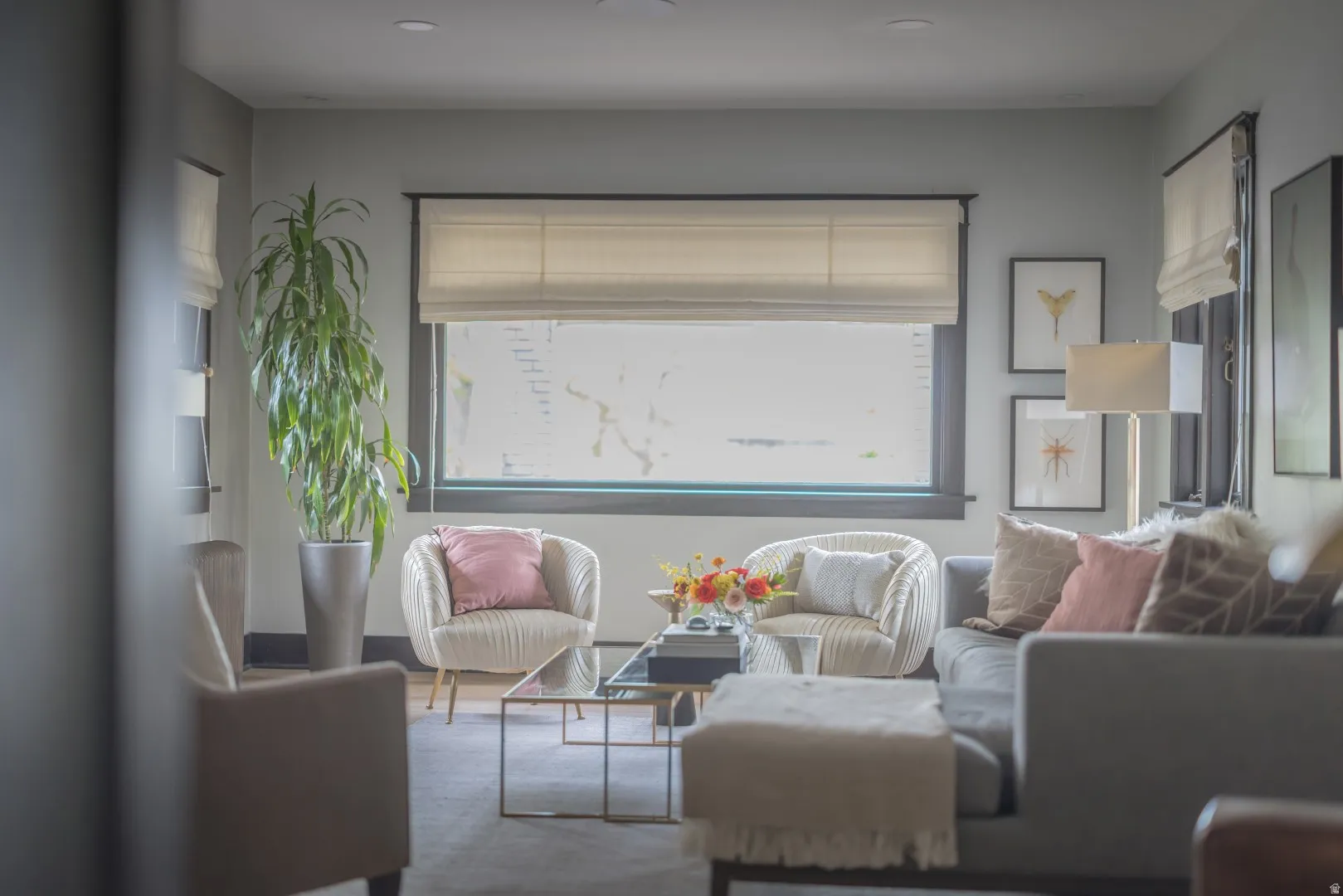 Bright, light-filled living room featuring expansive windows with motorized roller shades, neutral wall finishes, and polished concrete flooring