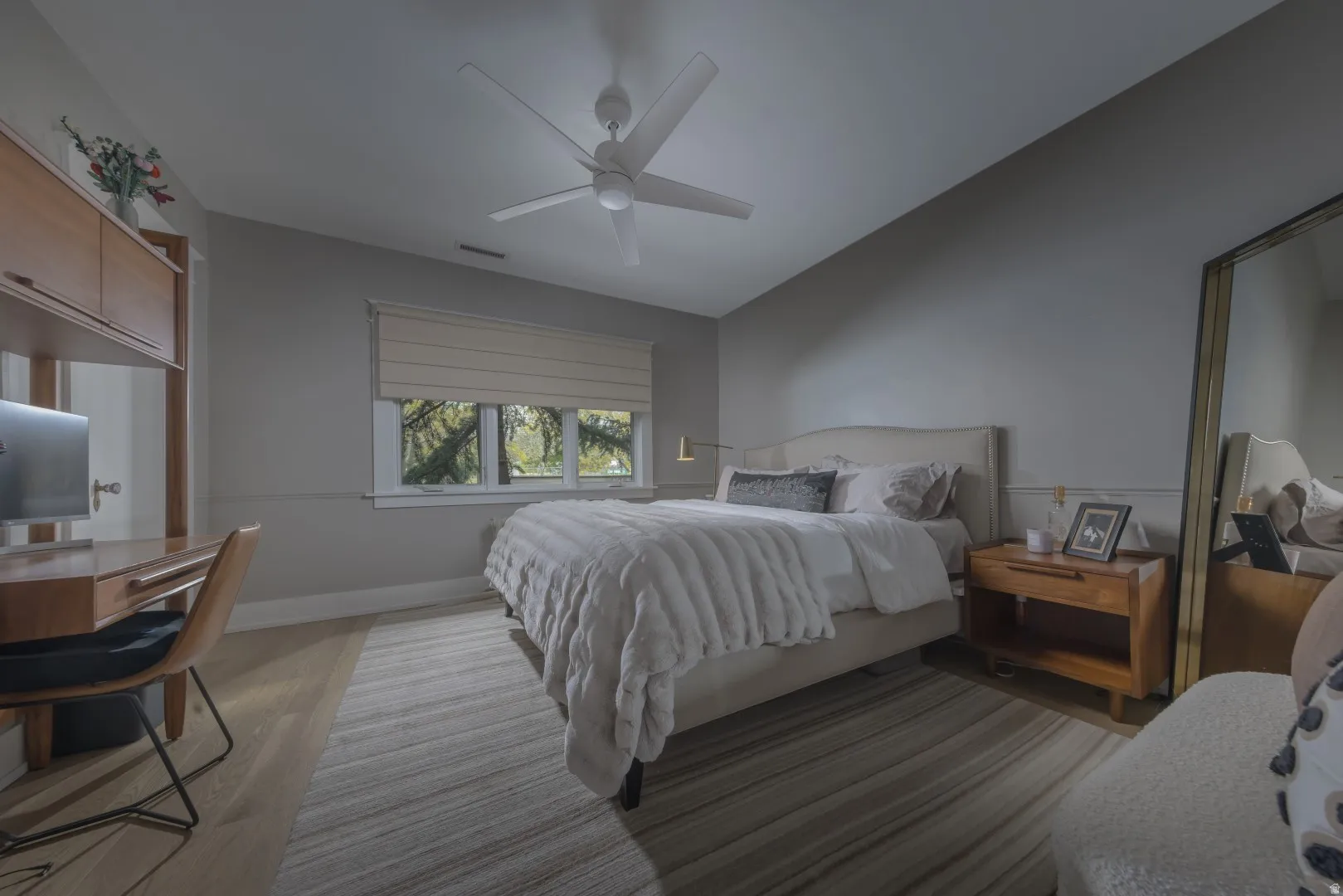 Light wood-finish flooring, built-in shelving, window with natural light, and ceiling fan