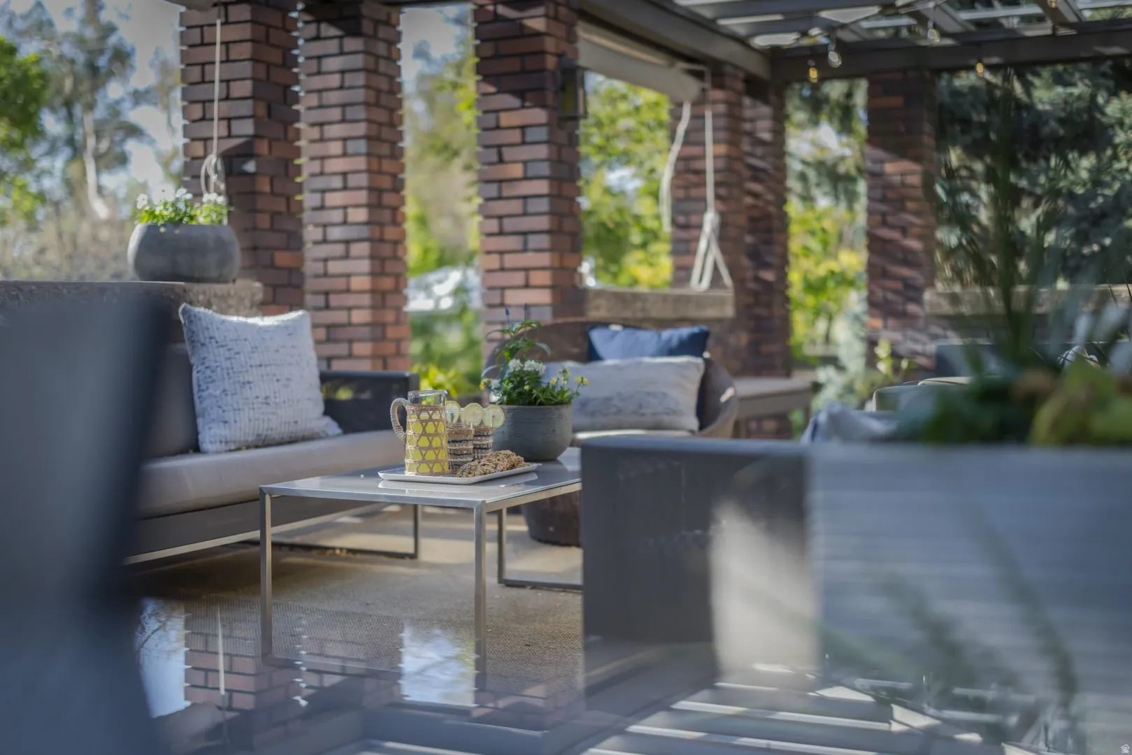 Covered outdoor patio featuring a pergola, brick columns, and concrete flooring