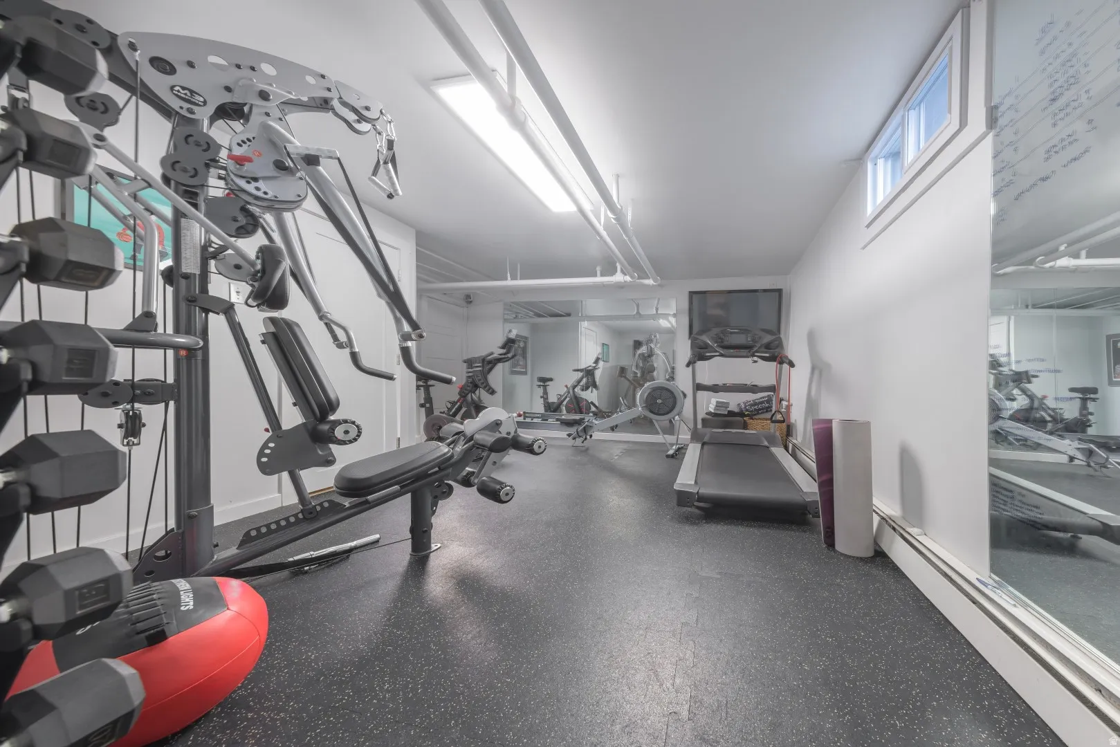 Dedicated fitness space featuring rubberized flooring, integrated ceiling lighting, and a full wall mirror