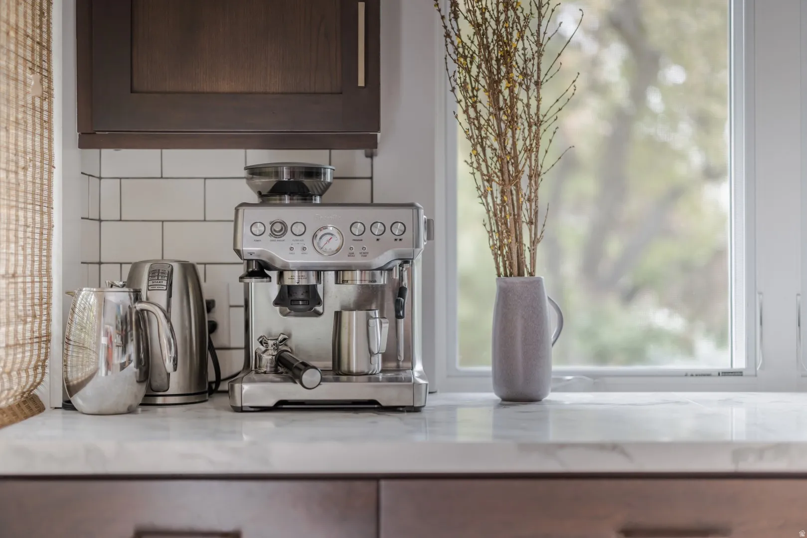 White subway tile backsplash, light-toned countertop, dark wood-finish cabinetry, and a white-framed window
