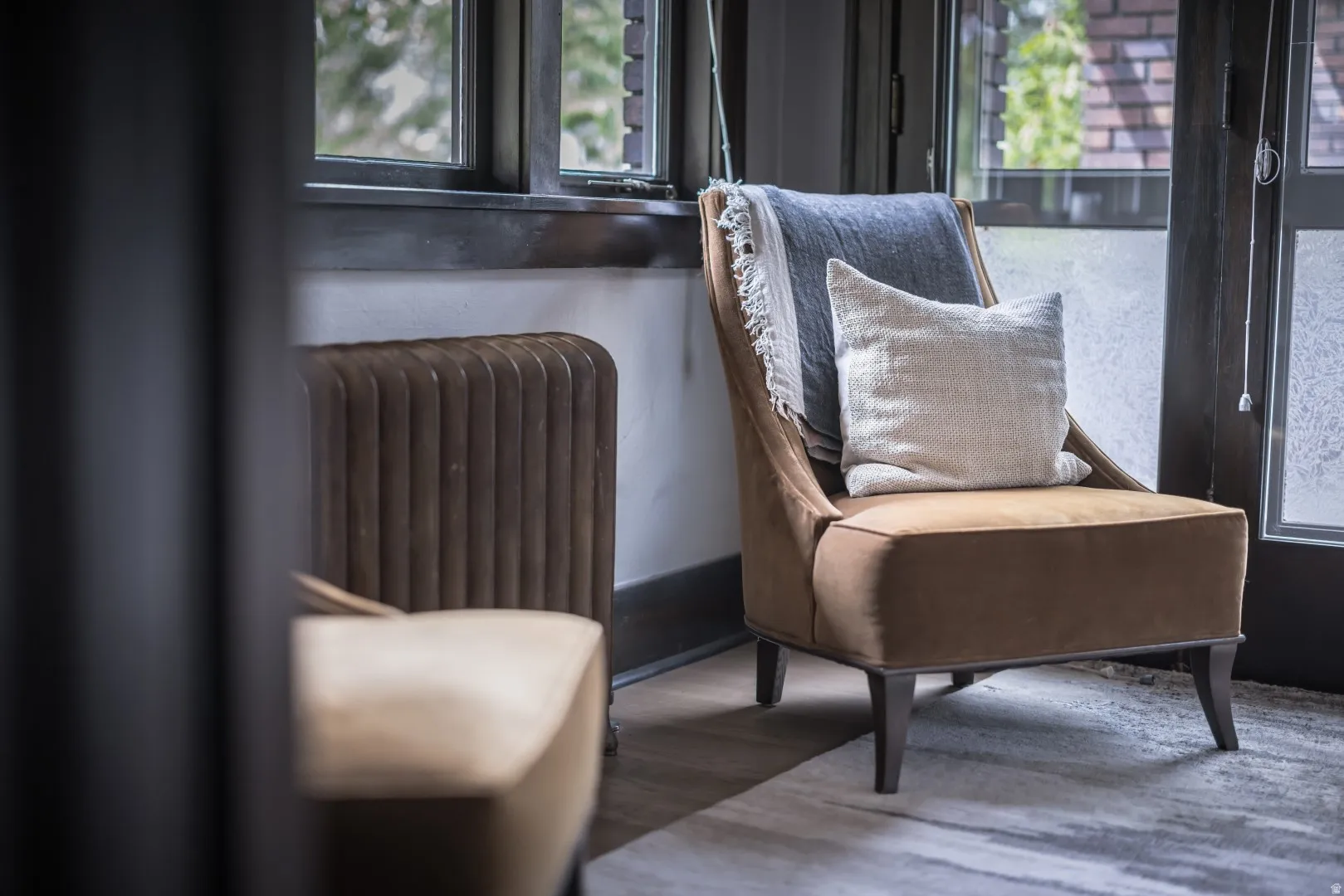 Dark-framed windows, a traditional fluted radiator, and light wood-finish flooring
