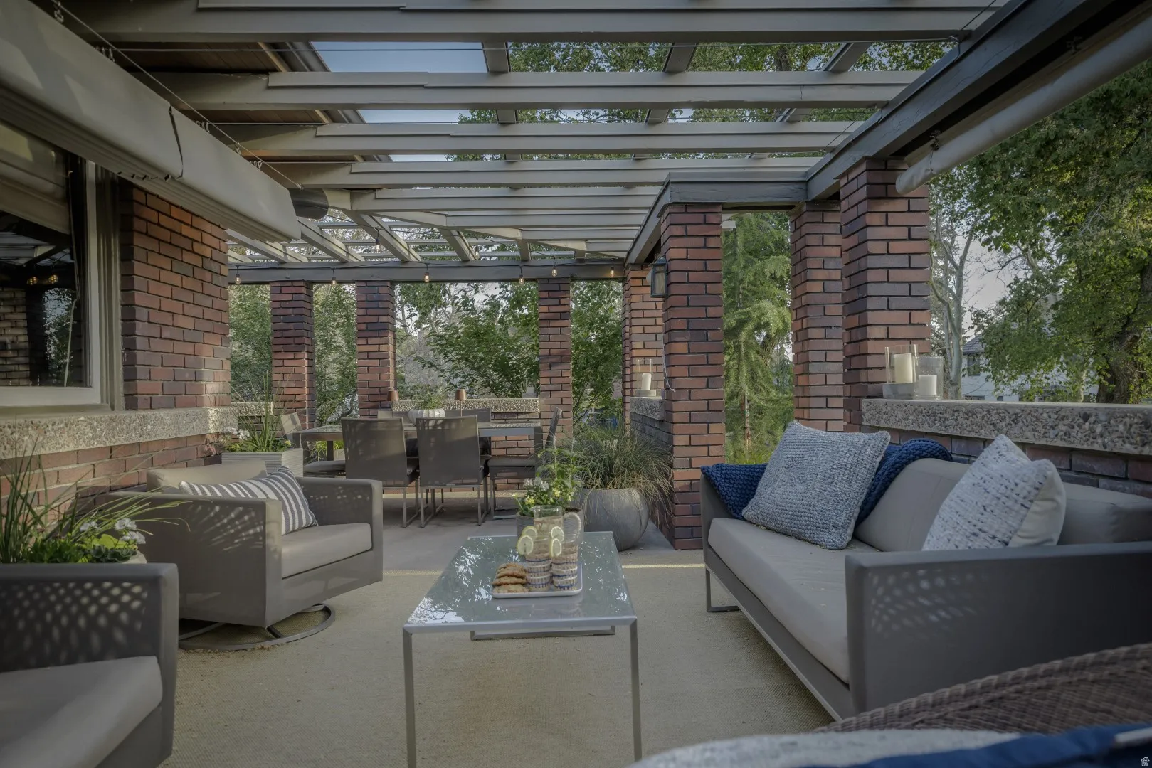 Covered outdoor patio with brick columns, slatted ceiling, and an integrated dining area