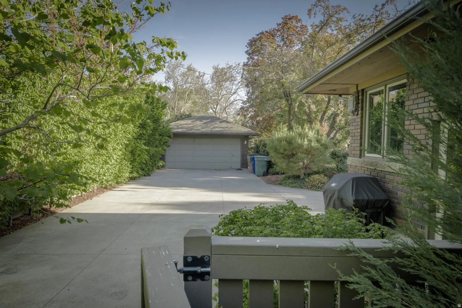 Brick exterior with multiple windows, concrete driveway, and detached garage structure