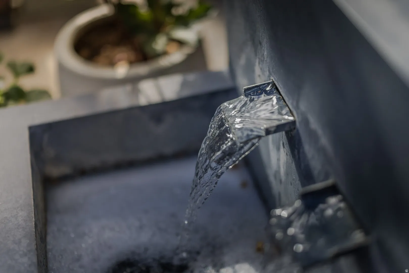 Water feature with a dark-toned basin and metal spouts