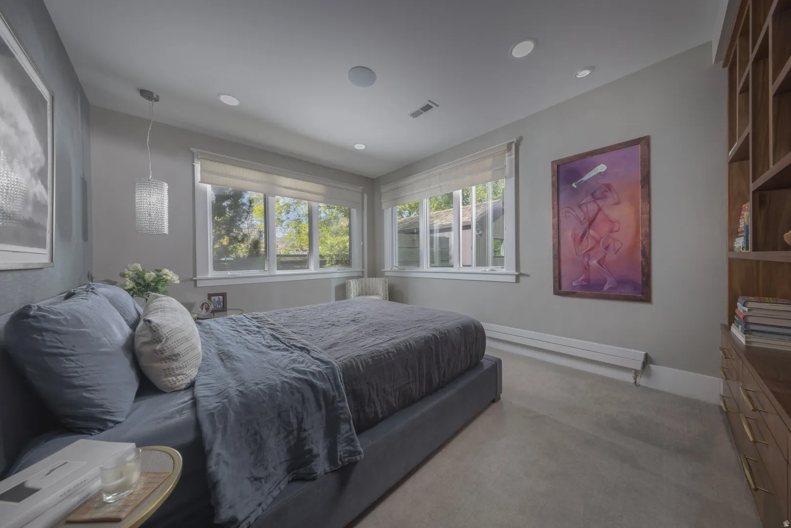 Primary Suite. Recessed lighting, wood-finish built-in shelving, and large windows with roller shades