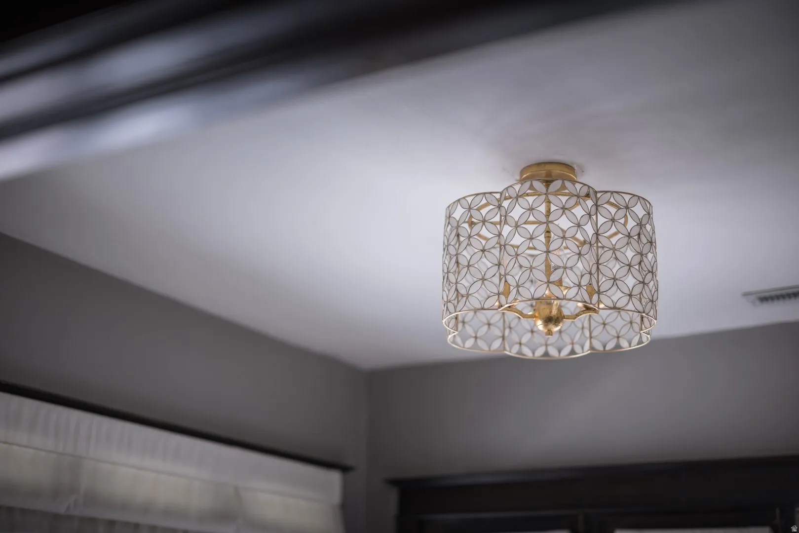 Ceiling-mounted light fixture featuring a decorative metal shade and a gold-tone finish