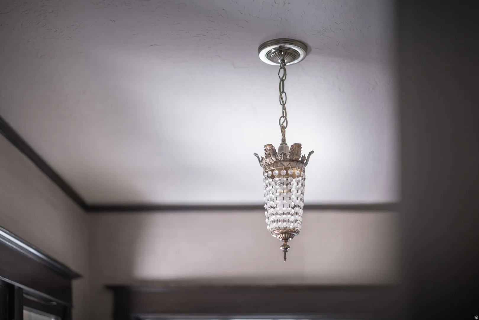 Decorative pendant light fixture with a crystal-adorned body, suspended from a chain and finished with a ceiling medallion