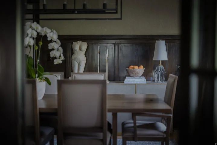 Elegant dining space showcasing neutral upholstered chairs, wood-finish table, and dark wood cabinetry with glass fronts
