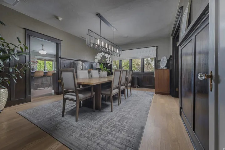 Wood-finish flooring throughout, featuring a linear chandelier and dark wood paneling