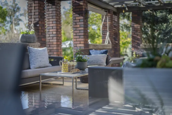 Covered outdoor patio featuring a pergola, brick columns, and concrete flooring