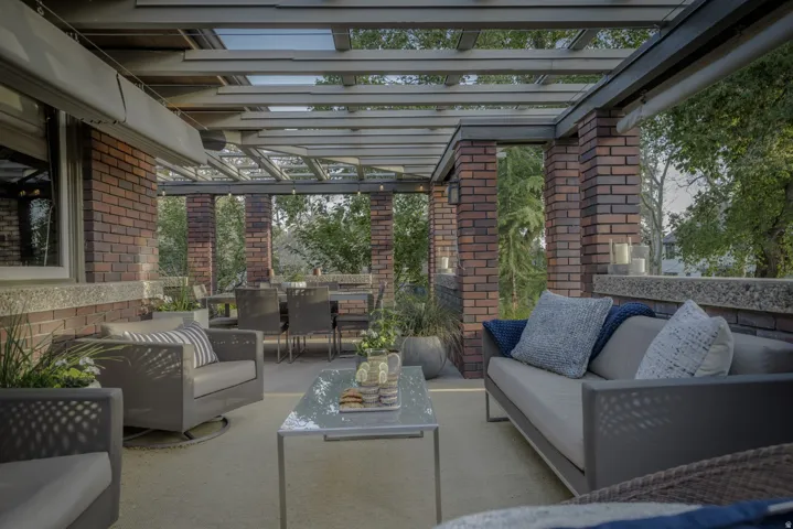 Covered outdoor patio with brick columns, slatted ceiling, and an integrated dining area