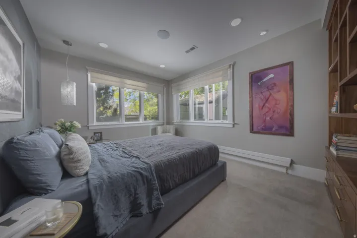 Primary Suite. Recessed lighting, wood-finish built-in shelving, and large windows with roller shades