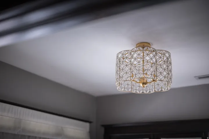 Ceiling-mounted light fixture featuring a decorative metal shade and a gold-tone finish