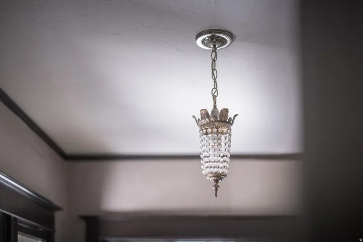 Decorative pendant light fixture with a crystal-adorned body, suspended from a chain and finished with a ceiling medallion