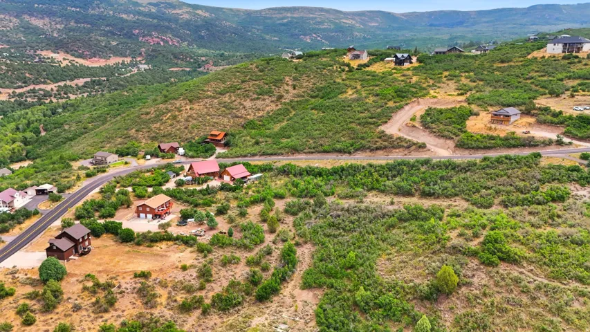 Expansive hillside properties with a paved road, natural landscaping, and distant mountain backdrops