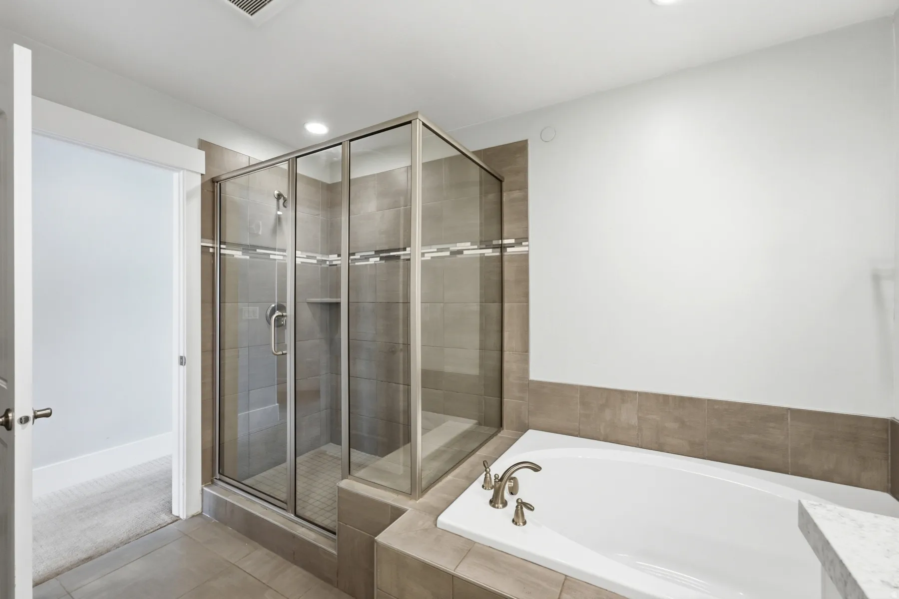 Walk-in shower with clear glass enclosure and tiled surround
