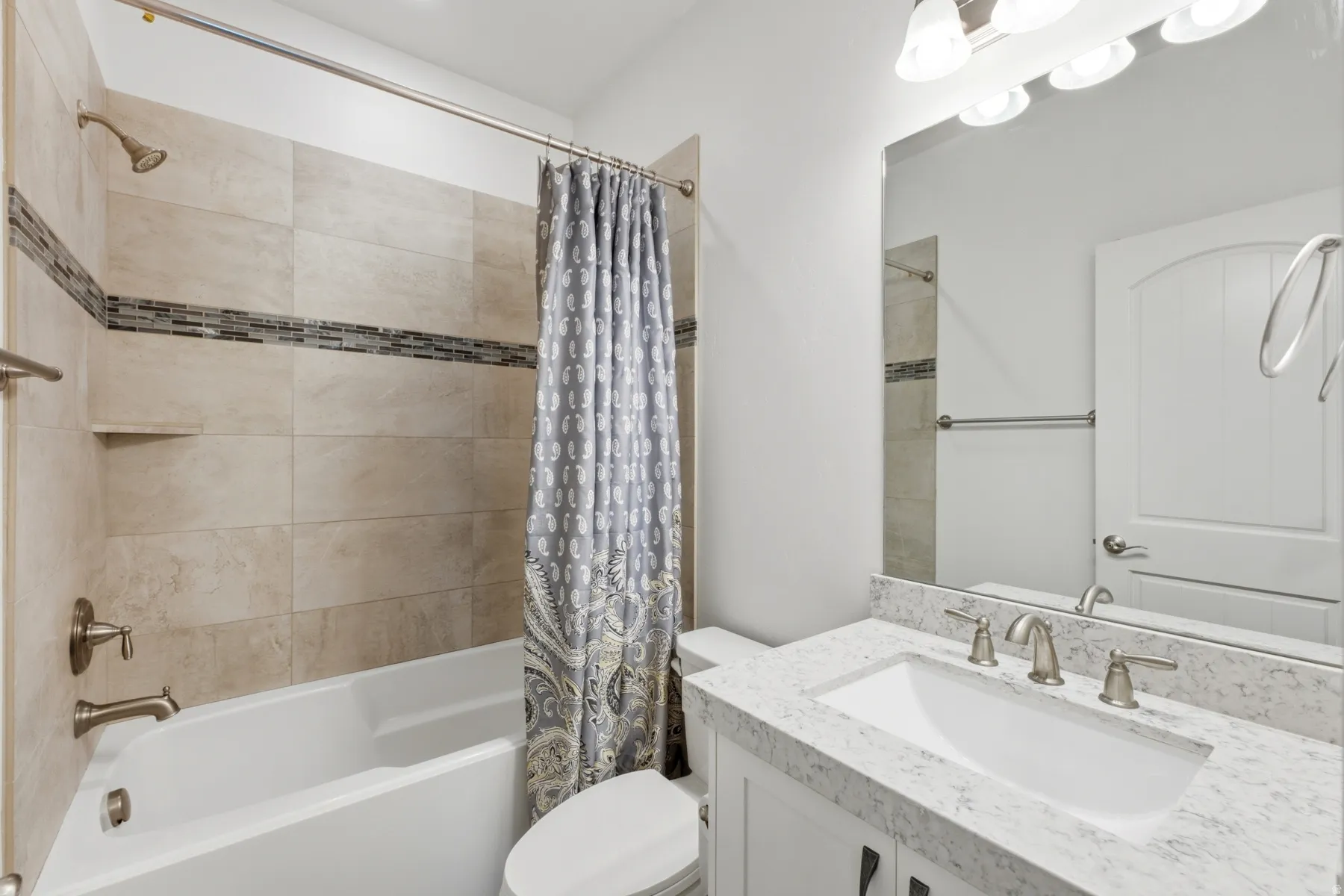 Bathtub with large format wall tiles and decorative mosaic band