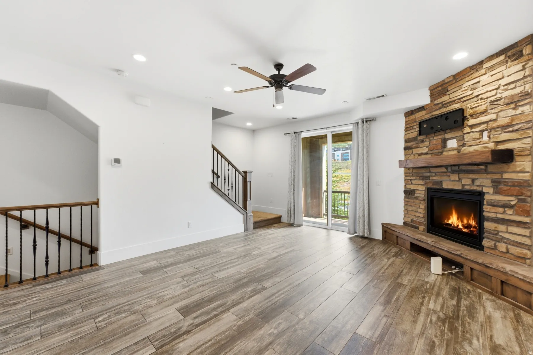 Wood-finish flooring throughout, featuring a stone-clad fireplace with wood mantel and hearth