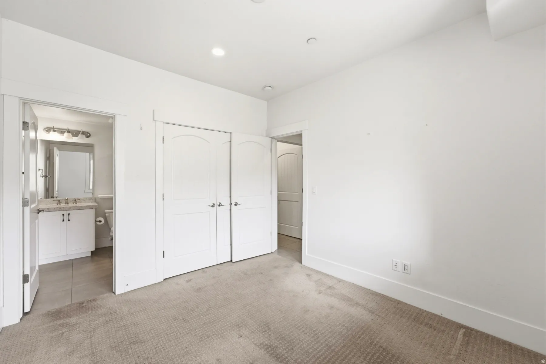 Recessed lighting, arched panel closet doors, and carpeted flooring