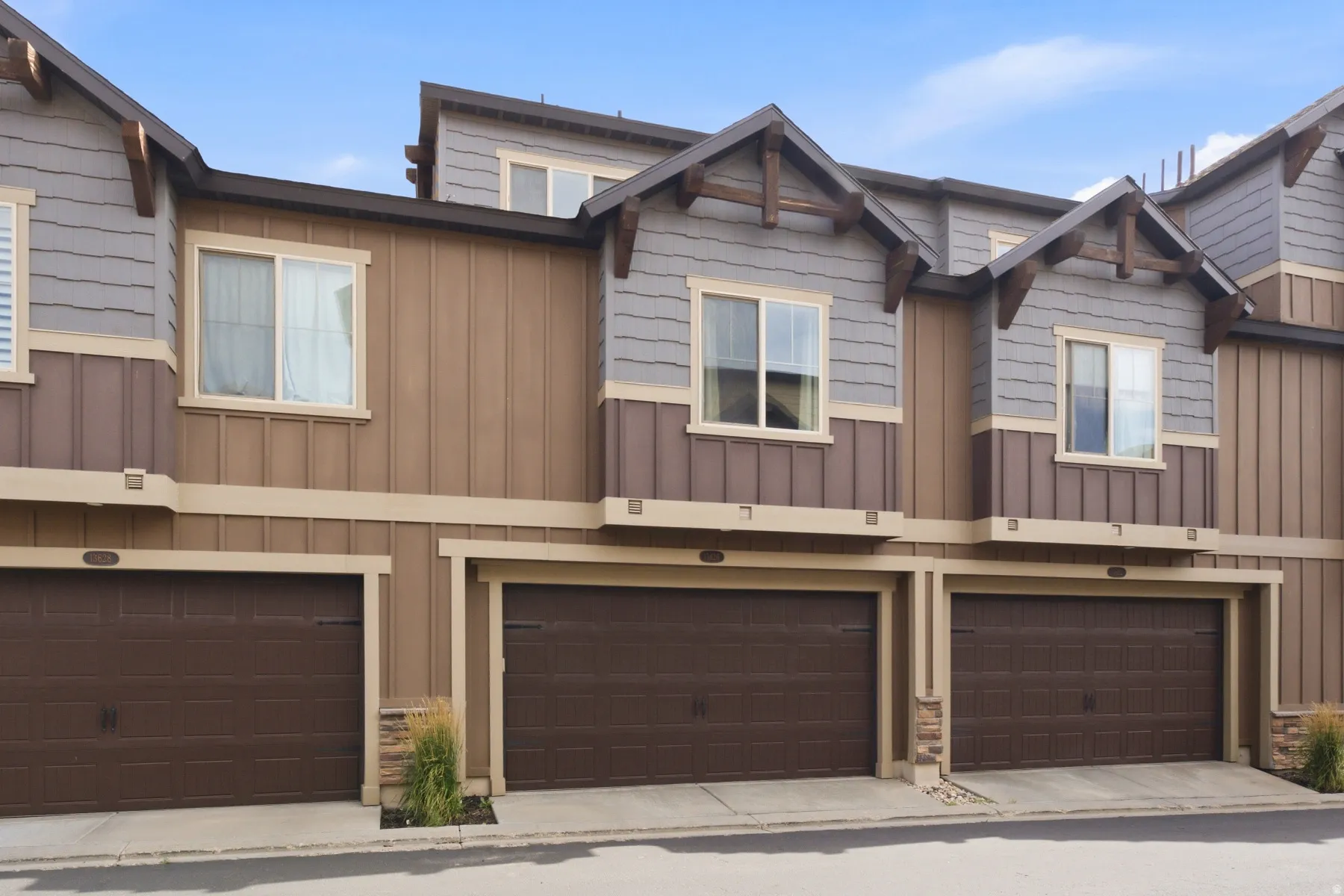 Multi-level facade with mixed material siding, individual garage doors, and decorative gable accents