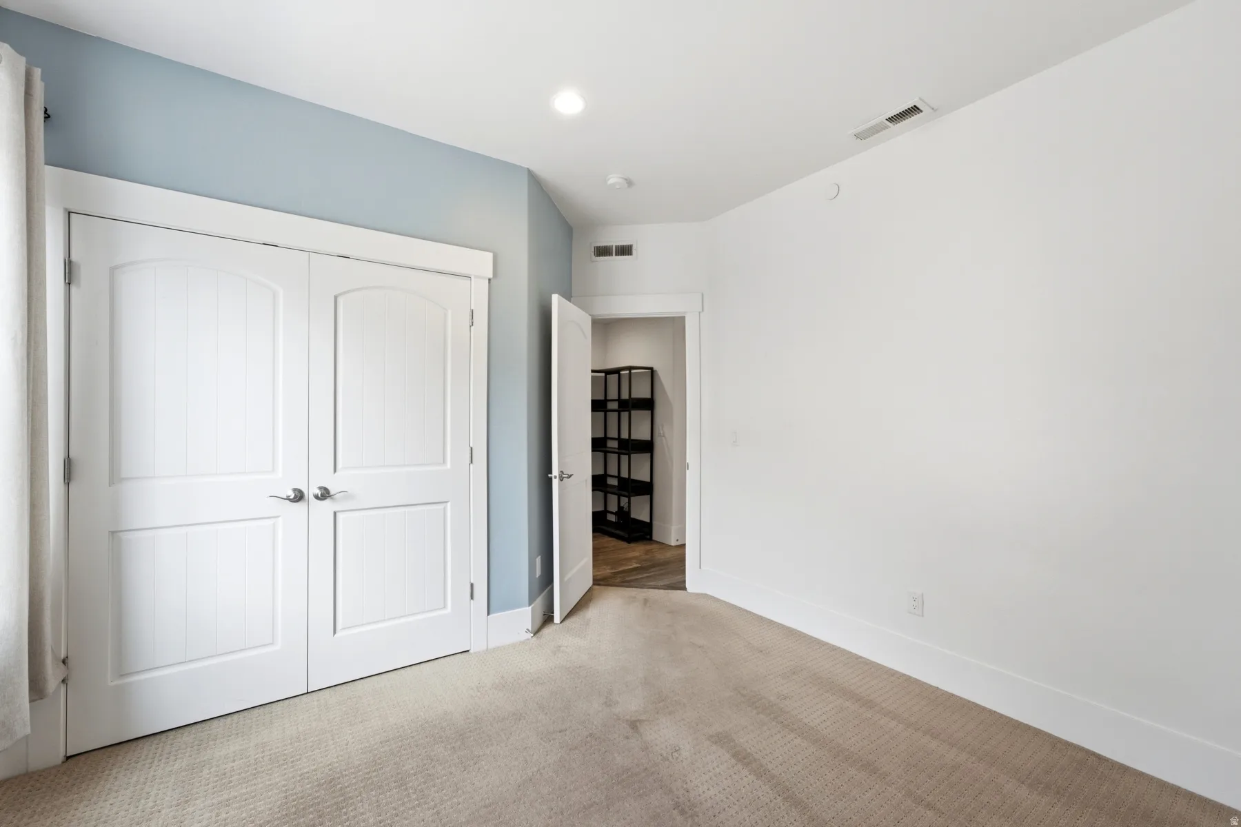 Carpeted flooring with white trim, double panel doors, and recessed lighting