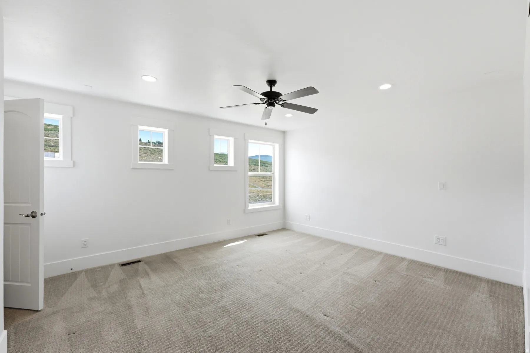 Recessed lighting, ceiling fan, white walls, multiple windows, and light-toned carpet