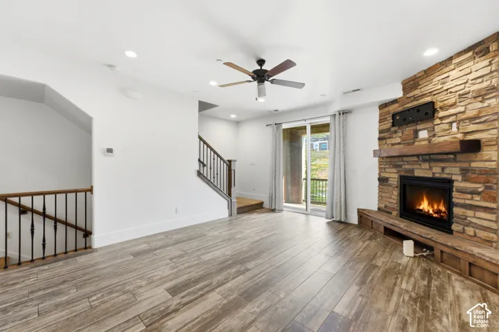 Wood-finish flooring throughout, featuring a stone-clad fireplace with wood mantel and hearth