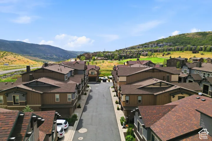 Townhome community with varied rooflines and siding colors, featuring a paved street and mountain scenery