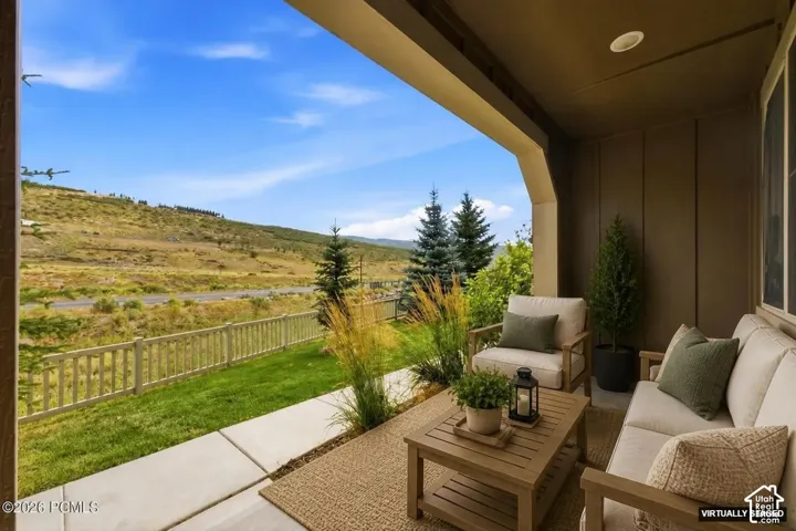 Covered outdoor patio with recessed lighting, concrete patio, and a natural wood fence bordering a grass area