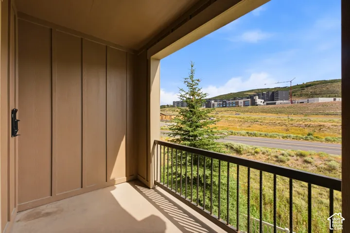 Private outdoor balcony with concrete flooring, wood-paneled wall, and black metal railing