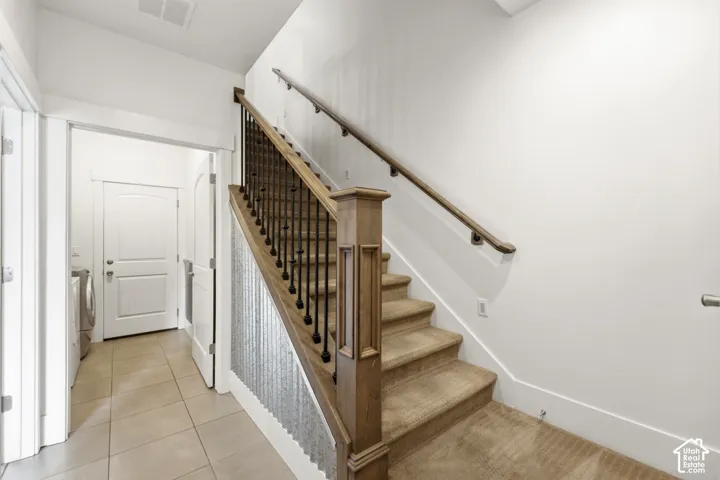 Carpeted staircase with wood-finish handrail and black metal balusters