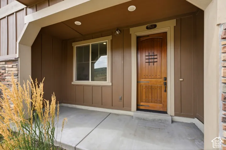 Covered entry with stone veneer accent, wood-paneled siding, and a solid wood entry door with wrought iron detailing