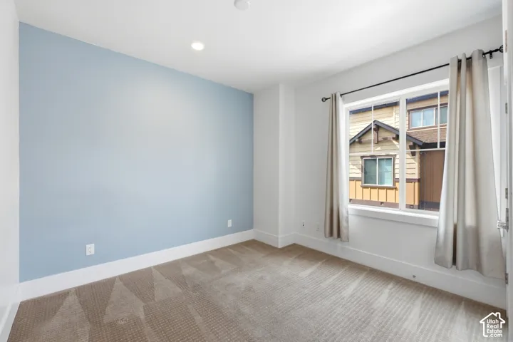 Recessed ceiling lighting, carpeting, a single window with white trim, and a light blue accent wall
