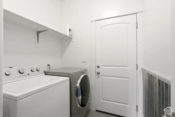 Laundry area featuring white walls, a single floating shelf, and a white paneled door with an arched top