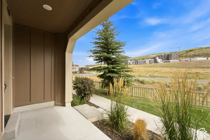 Covered concrete porch with recessed lighting, brown vertical panel siding, and a partial wood fence